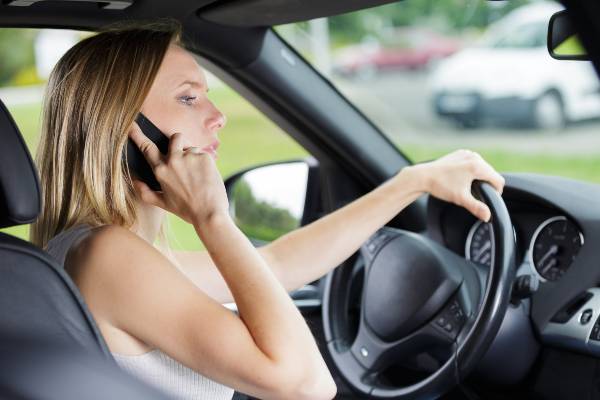 A woman talks on a cell phone while driving in West Virginia, indicating distracted driving.