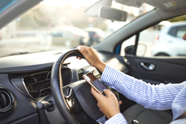 Distracted driver holds cellphone while driving