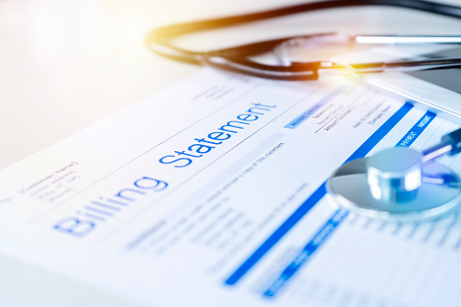 Health care billing statement with stethoscope, bottle of medicine for doctor's work in medical center stone background.