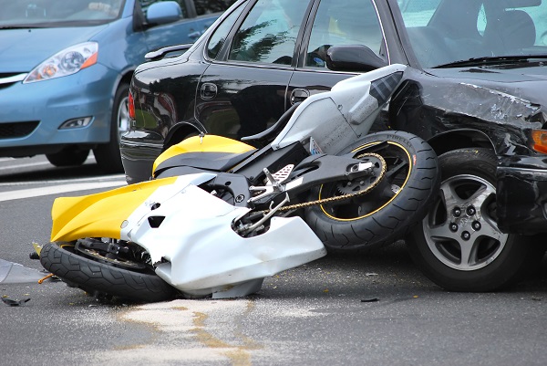 Yellow and black sportbike crashed up against a black sedan at the scene of a serious motorcycle accident on a busy road.