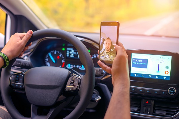 Male driver using smartphone to capture selfie pictures while driving.